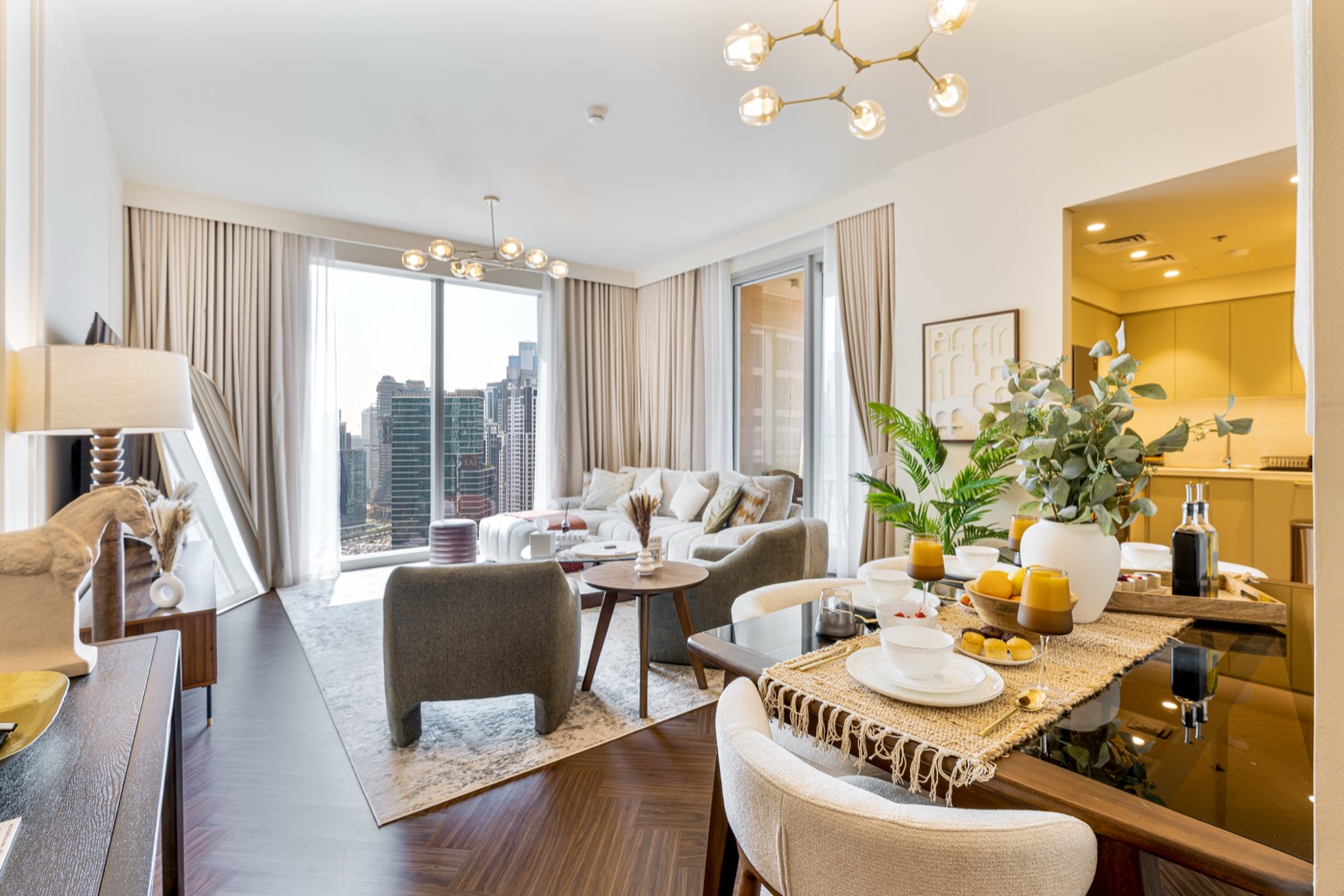 Sunlit living and dining room of a Mirage Stays apartment with floor-to-ceiling windows framing the Downtown Dubai skyline.