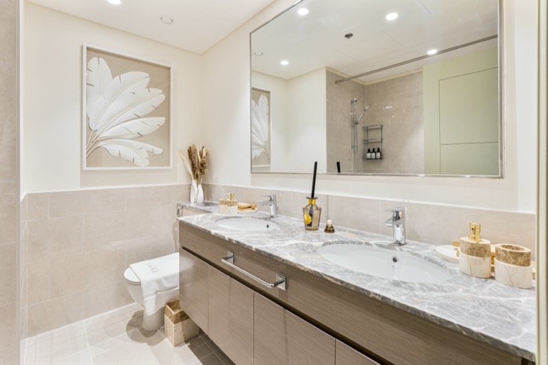 Marble double-vanity bathroom with warm lighting and considered styling.