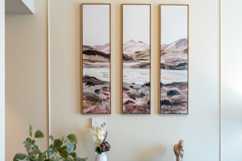 Framed watercolour triptych of desert landscapes above a console table inside a Mirage residence.